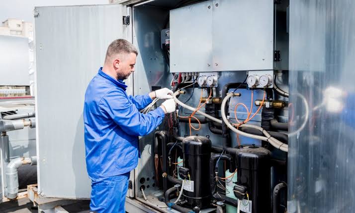 Technician servicing a large HVAC system and its internal components