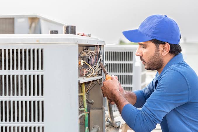 HVAC technician repairing an outdoor air conditioning unit